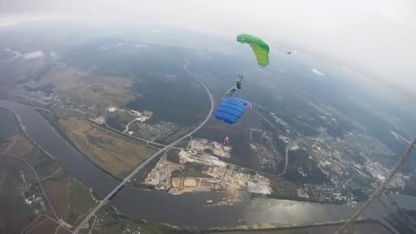 Skydivers pára-quedas no céu sobre o campo verde. Extremo. Noite nublada . — Vídeo de Stock