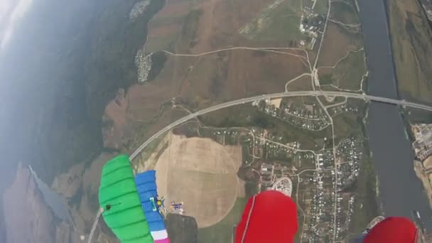 Los paracaidistas vuelan en el cielo sobre el campo verde. Paracaídas coloridos. Extremadamente. Nublado. . — Vídeos de Stock