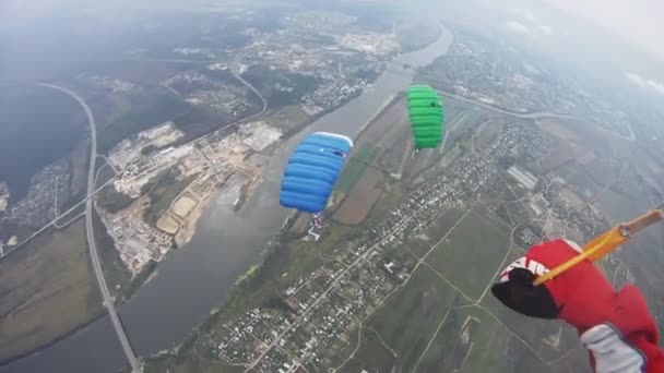 Parašutistů létat v nebi nad zelené pole. Barevné padáky. Extrémní. Bilance. — Stock video