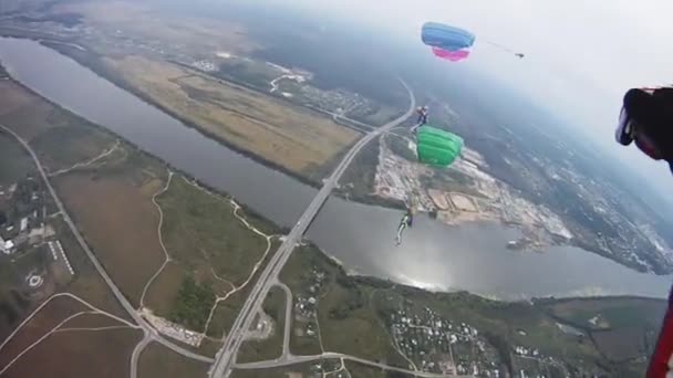 Skydivers yeşil alan üzerinde gökyüzünde uçmak. Renkli paraşüt. Aşırı. Tandem. — Stok video