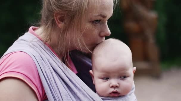 Jeune mère tenir bébé mignon en fronde sur l'aire de jeux. L'été. Embrasse. L'amour. Soins — Video