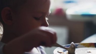 Küçük çocuk isteksizce tabak çorba masada yemek. Akşam yemeği. Çocukluk.