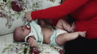 Kırmızı gömlekli genç anne elbise bebek Divan ağlayarak. Annelik. Bakım.