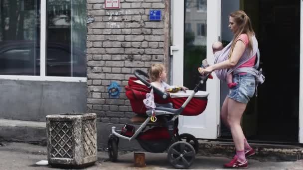 Modern med baby på lyftselen ta barnvagnen med son. Ge son kinder överraskning. — Stockvideo