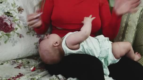 Jonge moeder in rood shirt borstvoeding kleine baby op Bank. Moederschap. — Stockvideo