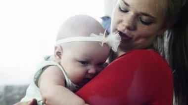 Genç anne eller şirin bebek üzerinde tutan kırmızı gömlekli. Öpücük. Seviyorum. Anne bakım.