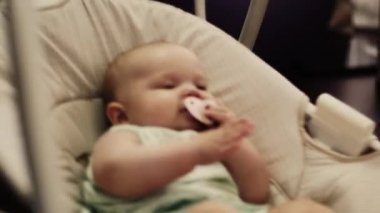 Küçük bebek salıncak daire üzerinde sway. Bebek ağzına kukla. Aile