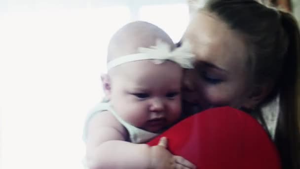 Giovane madre in camicia rossa che tiene su mani adorabile bambino. Bacio. Con amore. Cura . — Video Stock