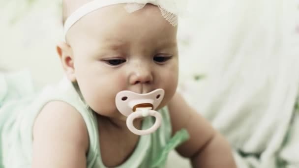 Adorable little baby lie on sofa with baby dummy. Cute girl. Looking in camera. — Stock Video