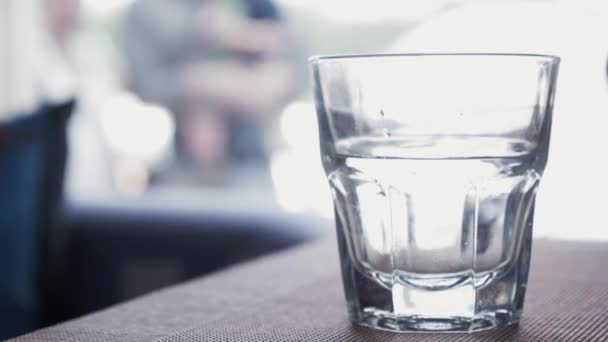 Copo de água em cima da mesa no restaurante. Bebe. Fechar — Vídeo de Stock