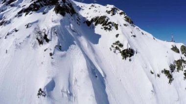 Quadrocopter ateş snowboard freestyle karlı dağın zirvesine üzerinden. Toz