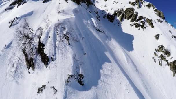 Quadrocopter schieten snowboarder gratis ritje van piek van besneeuwde berg. Bij gebreke — Stockvideo