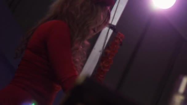 Дівчина Джі в червоній сукні обертається на поворотному столі в нічному клубі. Виступ. Підняти руку — стокове відео