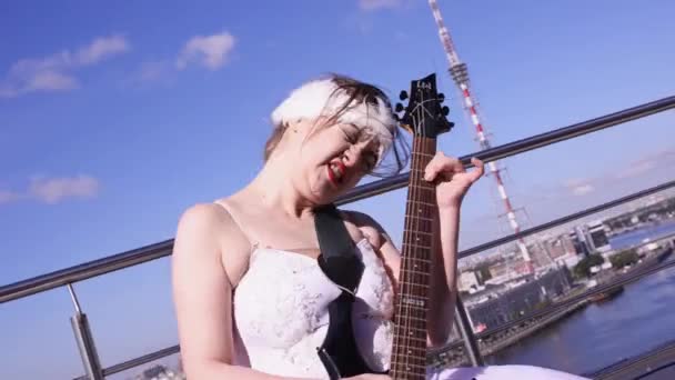 Chica en traje blanco bailarina tocar la guitarra eléctrica en primera línea de mar en el día soleado. Baile. Rock and roll — Vídeos de Stock