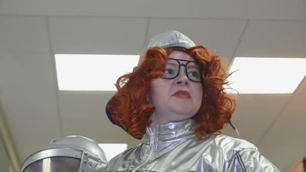 Woman with red curly hair in grey space suit, glasses speaking, gesture. Helmet in hands. Surrealism — Stock Video