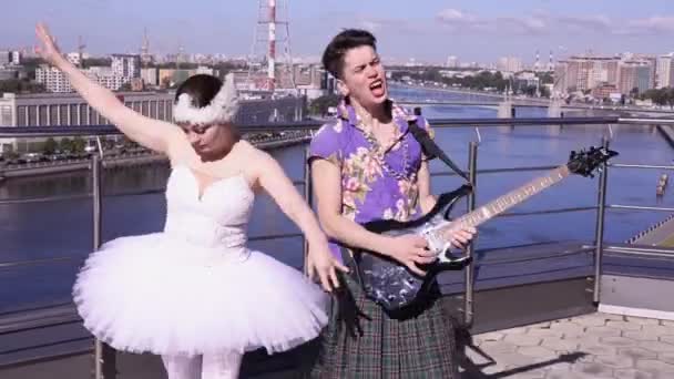 Man in skirt play electric guitar on street in sunny day. Girl dance in ballerina suit. Crazy style — Stock Video