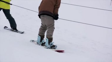 Karlı dağ yamacında iki snowboard binmek. Yarışma. Meydan okuma. Üniforma. İp. Güneş gözlüğü