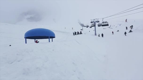 Snowboarder springen op blauwe ronde springplank besneeuwde pad. Uniform. Kabelspoorweg. Mensen — Stockvideo