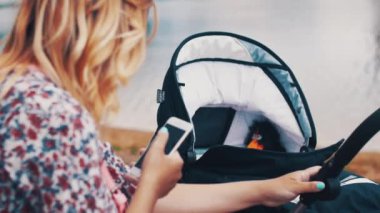 Anne Bebek arabası ve gölde smartphone kullanarak sway. Yaz güneşli gün.
