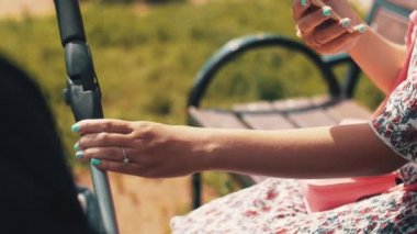 Anne Bebek arabası sway ve Park telefon almak. Yaz güneşli gün.
