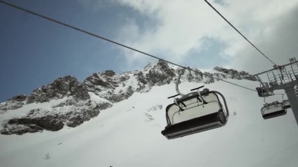 Vista degli impianti di risalita cavalcare giù senza persone a montagne innevate. Località sciistica. Snowboard. Cabina aperta — Video Stock