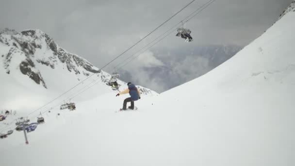 Snowboarder fahren auf schneebedeckten Bergen den Hang hinunter. Uniform. Skilifte. Skigebiet. Extremes Hobby
