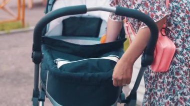 Anne ile Çocuk oyun alanı üzerinde bebek arabası. Yaz günü. Annelik.