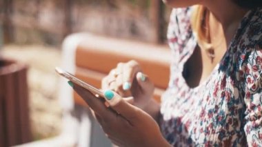 Mutlu aşk kaç bankta oturan smartphone kullanarak. Yaz rüzgarlı gün.
