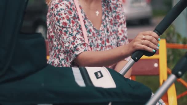 Giovane madre ondeggiare carrozzina sulla strada. Giornata estiva ventosa. Maternità . — Video Stock