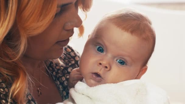 Мама держит маленького милого ребенка с голубыми глазами. Материнство. Взгляд младенца в камеру . — стоковое видео