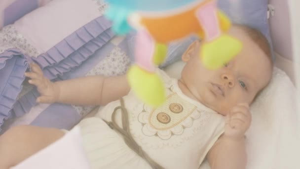 Симпатичный малыш лежит в кроватке и смотрит на движущиеся красочные игрушки. Материнство. Материнство . — стоковое видео