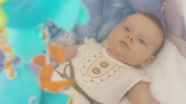 Renkli oyuncaklar hareketli izlerken beşik küçük bebek yalan. Annelik. Annelik.