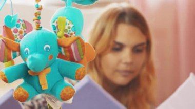 Küçük bebek yalan anne tutun el beşik izlerken renkli hareketli oyuncaklar. Aile