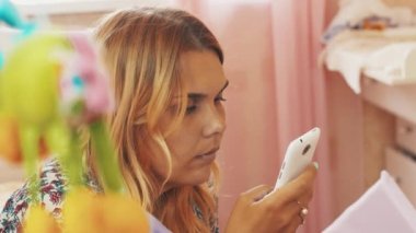Anne küçük bebek yalan beşik, oyuncaklar ile oturmak smartphone kullanarak. Annelik