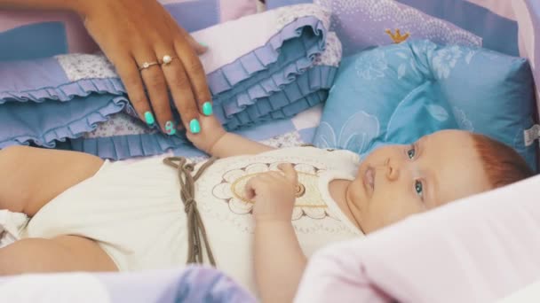Mother hold hand little baby lie in crib watching colorful moving toys above him — Stock Video