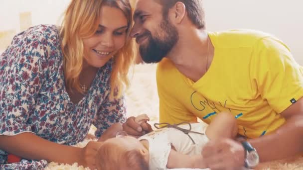 Los padres jóvenes felices se comunican con el pequeño bebé. Familia. Padre y madre beso — Vídeos de Stock