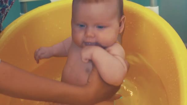 Moeder zwemmen beetje schattige baby met blauwe ogen. Gele bad. Moederschap. — Stockvideo