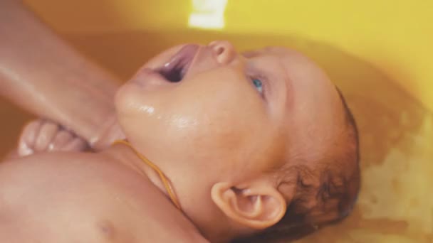 Mother bathing adorable baby with blue eyes. Yellow bath. Motherhood. Care — Stock Video