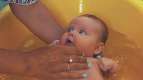 Madre bañando pequeño bebé lindo con ojos azules. Baño amarillo. Maternidad. Cuidado. — Vídeo de stock