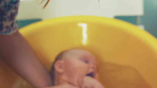 Mutter badet kleines süßes Baby mit blauen Augen. Gelbes Bad. Mutterpflege. — Stockvideo