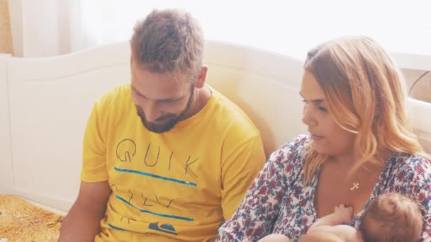 Padres jóvenes en casa con un bebé pequeño. Familia. Padre juega en la tableta. Felicidad — Vídeo de stock