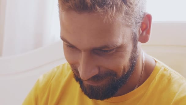Portrait of bearded adult man in yellow shirt play in game on tablet. Smile. — Stock Video