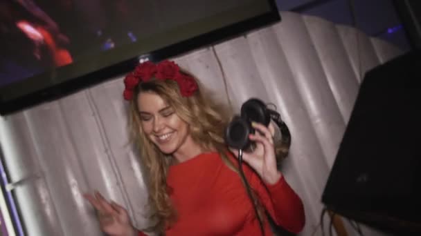 Gledelig dj-jente i rød kjole, med krans på hodet, hopp på platespiller i klubben. Brystkasse – stockvideo