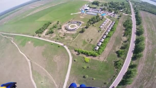 Professionella fallskärmshoppare flyger i himlen ovanför vägen. Soliga. Landning på grönt fält — Stockvideo