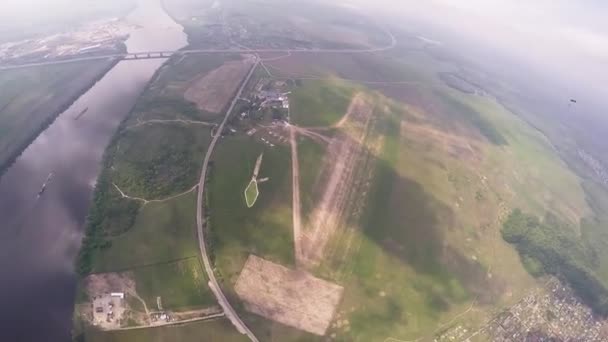 Profesionální parašutista létat na obloze nad zelenými poli, řeka. Sun. krajina. — Stock video