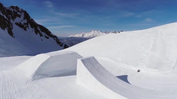 Квадрокоптер стріляє сноубордистським стрибком зі трампліна. Сніжна гора. Ландшафтний — стокове відео