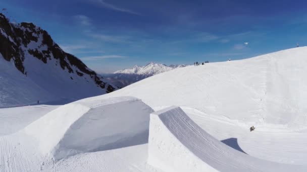 Quadrocopter atirar snowboarder salto de trampolim. Montanhas nevadas. Acrobacia — Vídeo de Stock