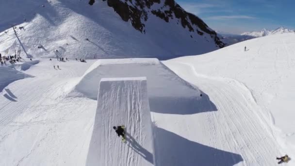 Quadrocopter は、飛び込み板からスノーボーダー ジャンプを撮影します。雪の山。(日) 速度 — ストック動画