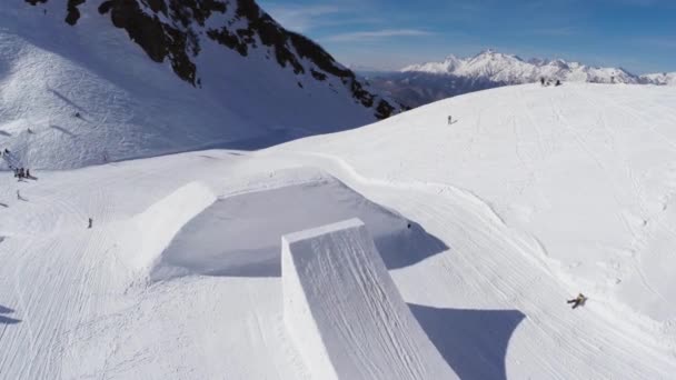 Quadrocopter lő snowboardos ugrás az ugródeszka, hogy bukfenc. Hegyek — Stock videók