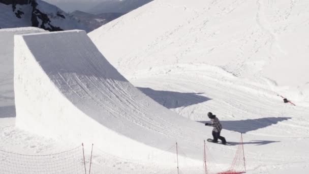 Snowboardåkare rida på språngbräda. Göra full flip i luften. Solig dag. Bergen. — Stockvideo